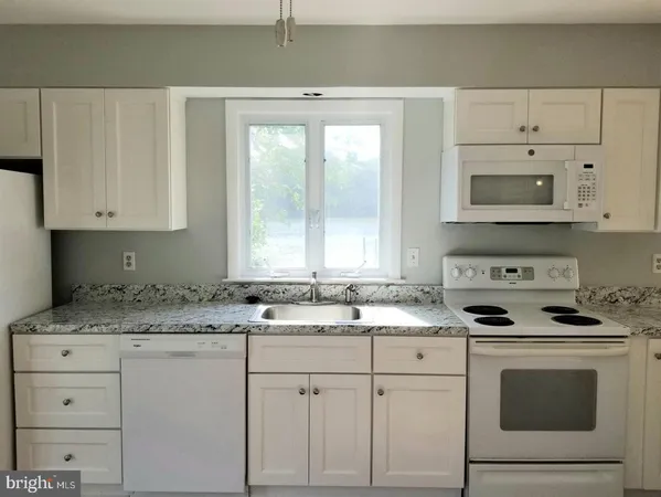 a kitchen with white cabinets and white appliances