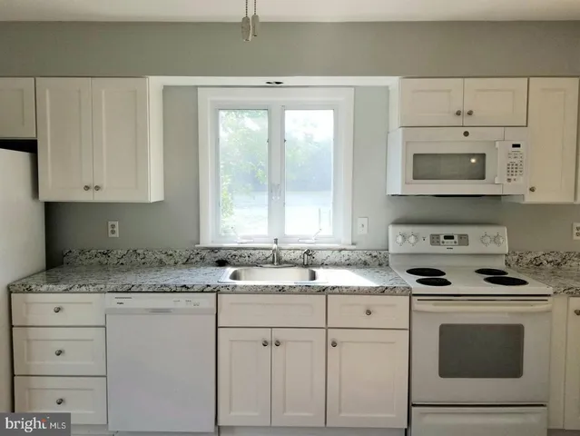 a kitchen with white cabinets and white appliances