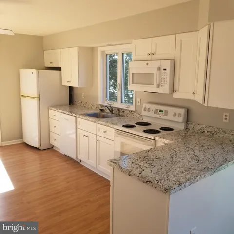 a view of a kitchen with a sink dishwasher and wooden floor
