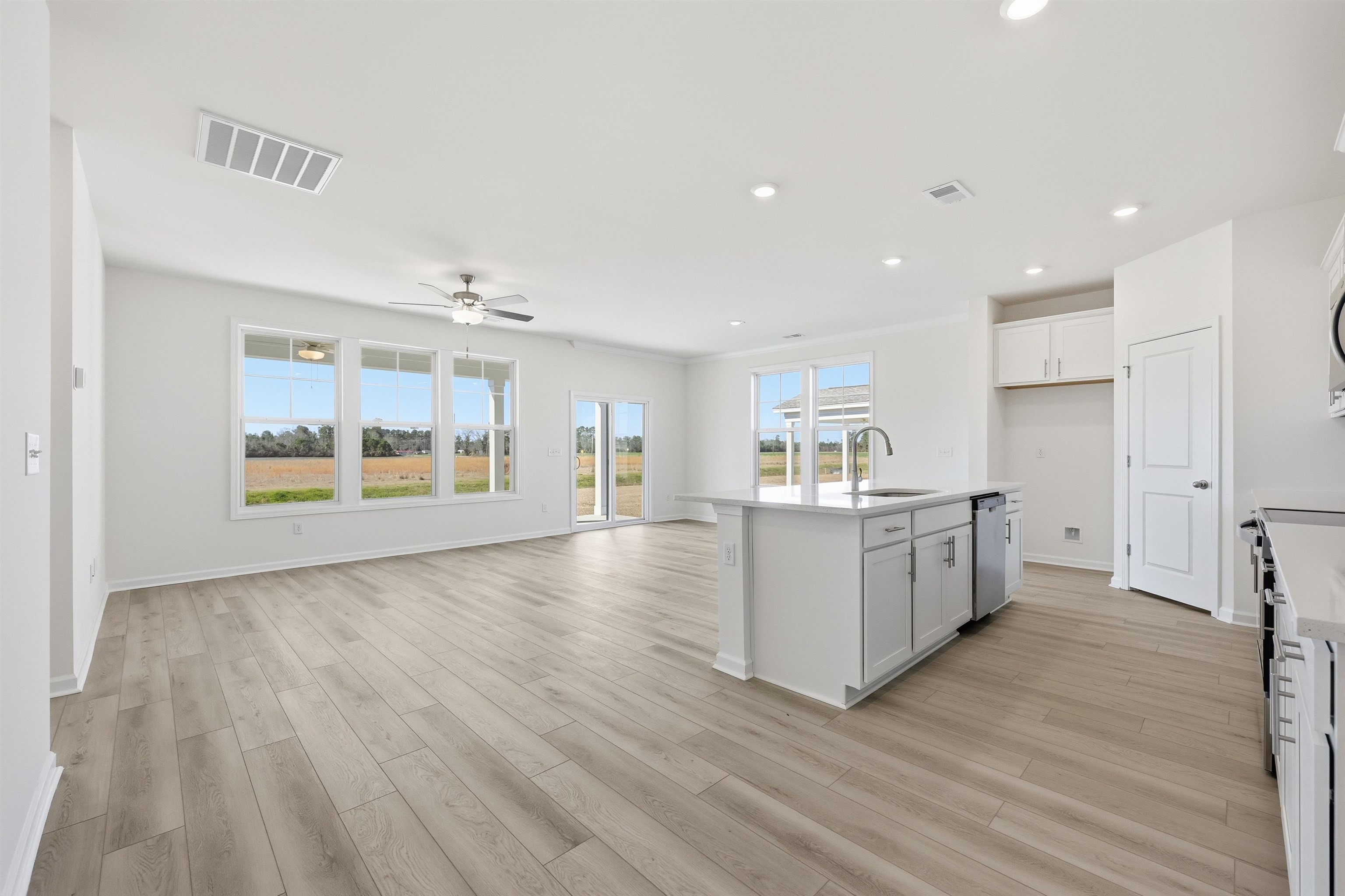 141 River Birch Drive Loris, SC 29569 - Photo 35 of 37 Kitchen featuring a kitchen island with sink, white cabinets, open floor plan, light wood-type flooring, and a ceiling fan