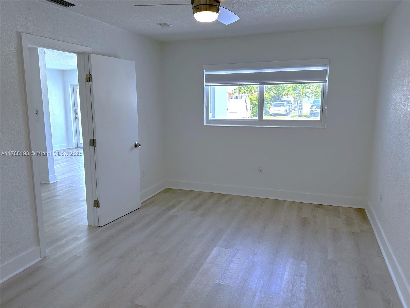 11232 Southwest 5th Street, Unit 2 Sweetwater, FL 33174 - Photo 11 of 24 a view of an empty room with wooden floor and a window