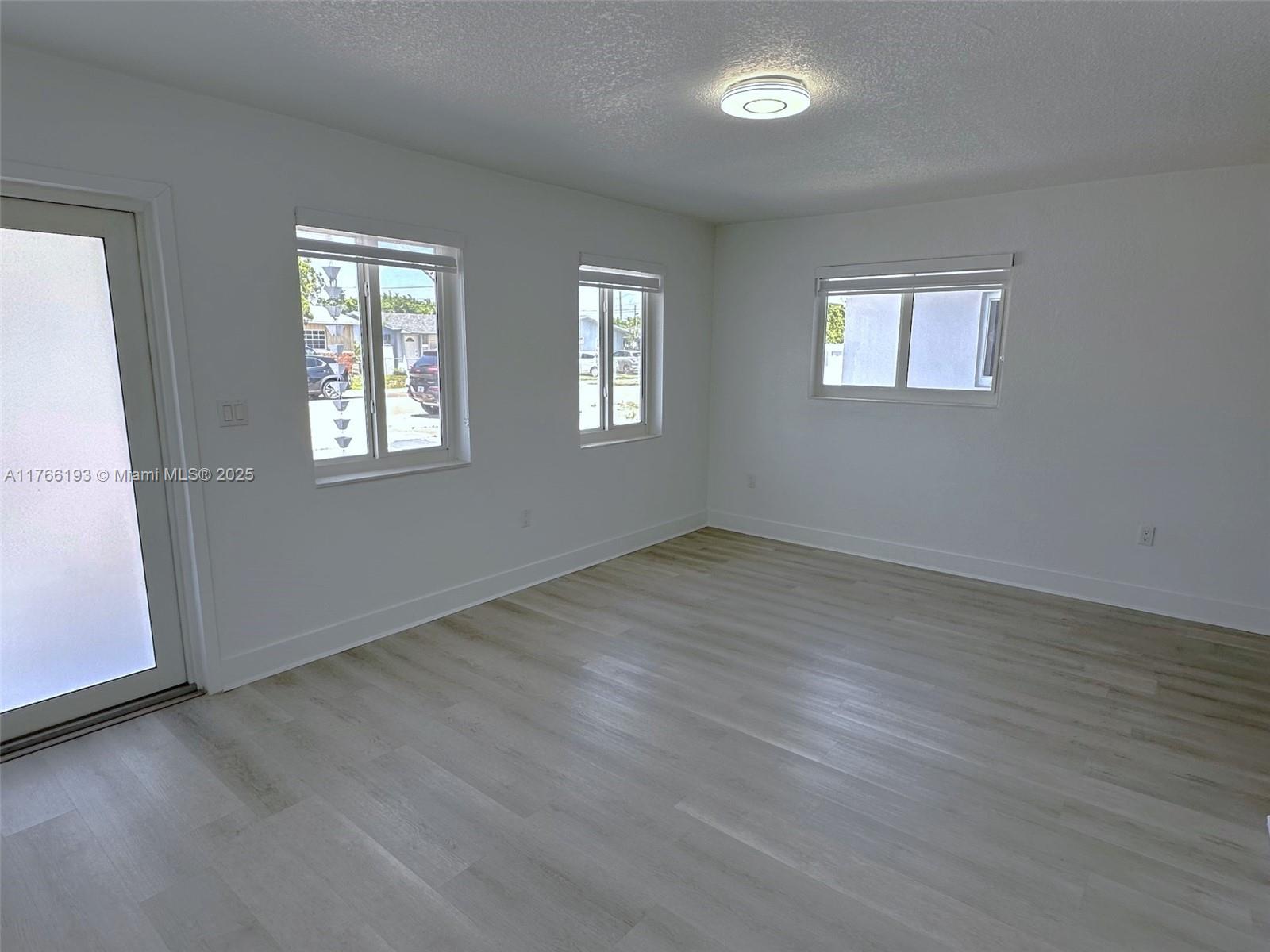 11232 Southwest 5th Street, Unit 2 Sweetwater, FL 33174 - Photo 20 of 24 a view of an empty room with wooden floor and a window