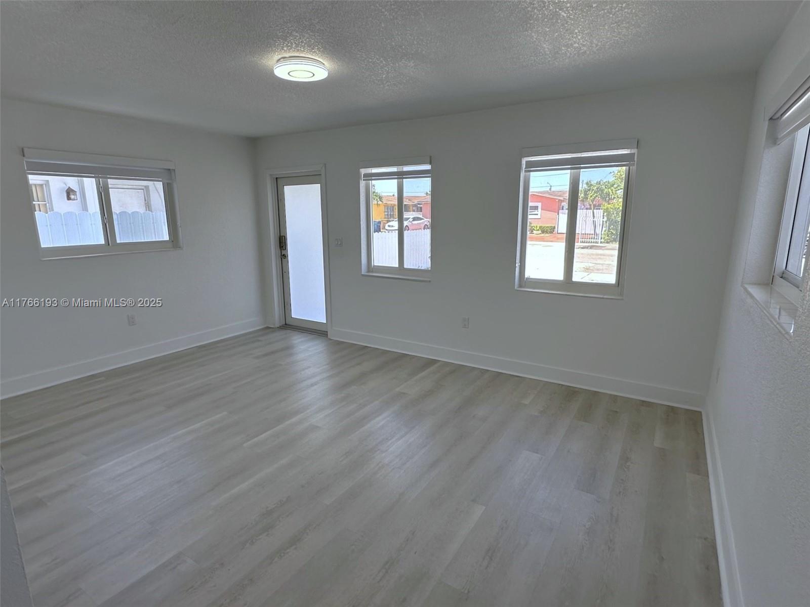 11232 Southwest 5th Street, Unit 2 Sweetwater, FL 33174 - Photo 3 of 24 a view of an empty room with wooden floor and a window