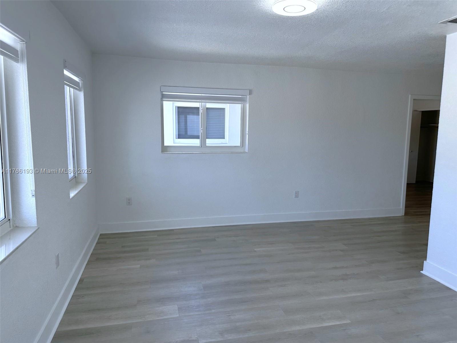 11232 Southwest 5th Street, Unit 2 Sweetwater, FL 33174 - Photo 4 of 24 a view of an empty room with wooden floor and a window