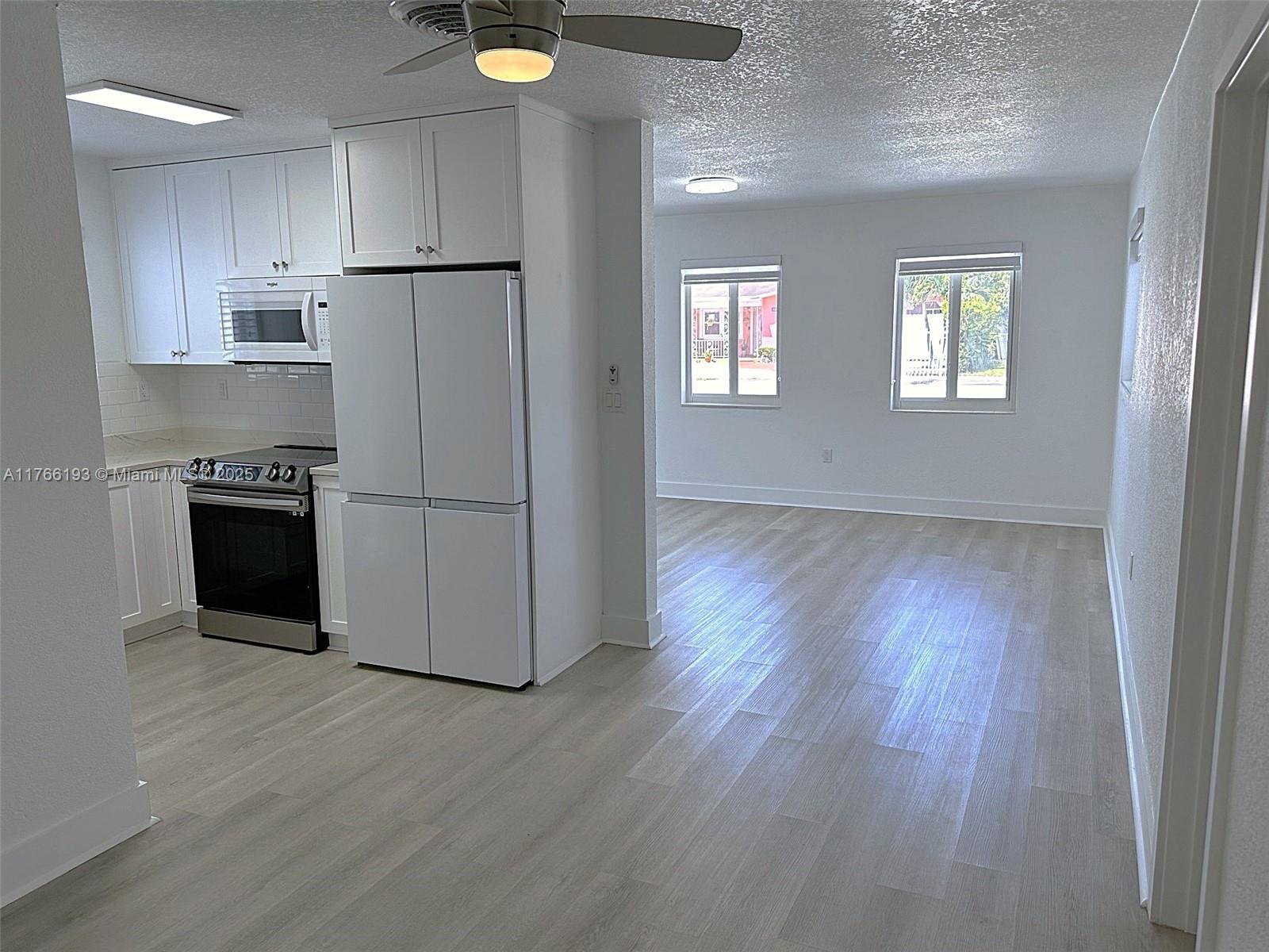 11232 Southwest 5th Street, Unit 2 Sweetwater, FL 33174 - Photo 5 of 24 a kitchen with wooden floors and refrigerator