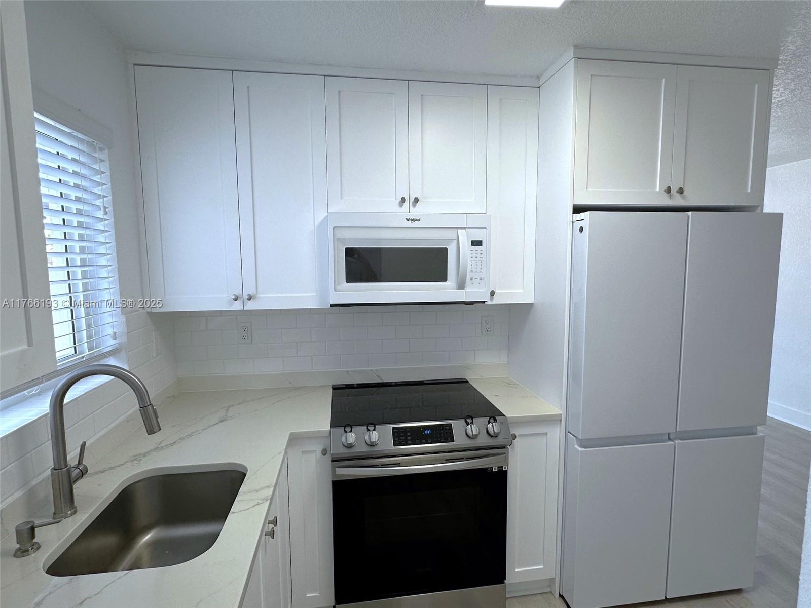 11232 Southwest 5th Street, Unit 2 Sweetwater, FL 33174 - Photo 7 of 24 a kitchen with refrigerator a stove a sink and cabinets