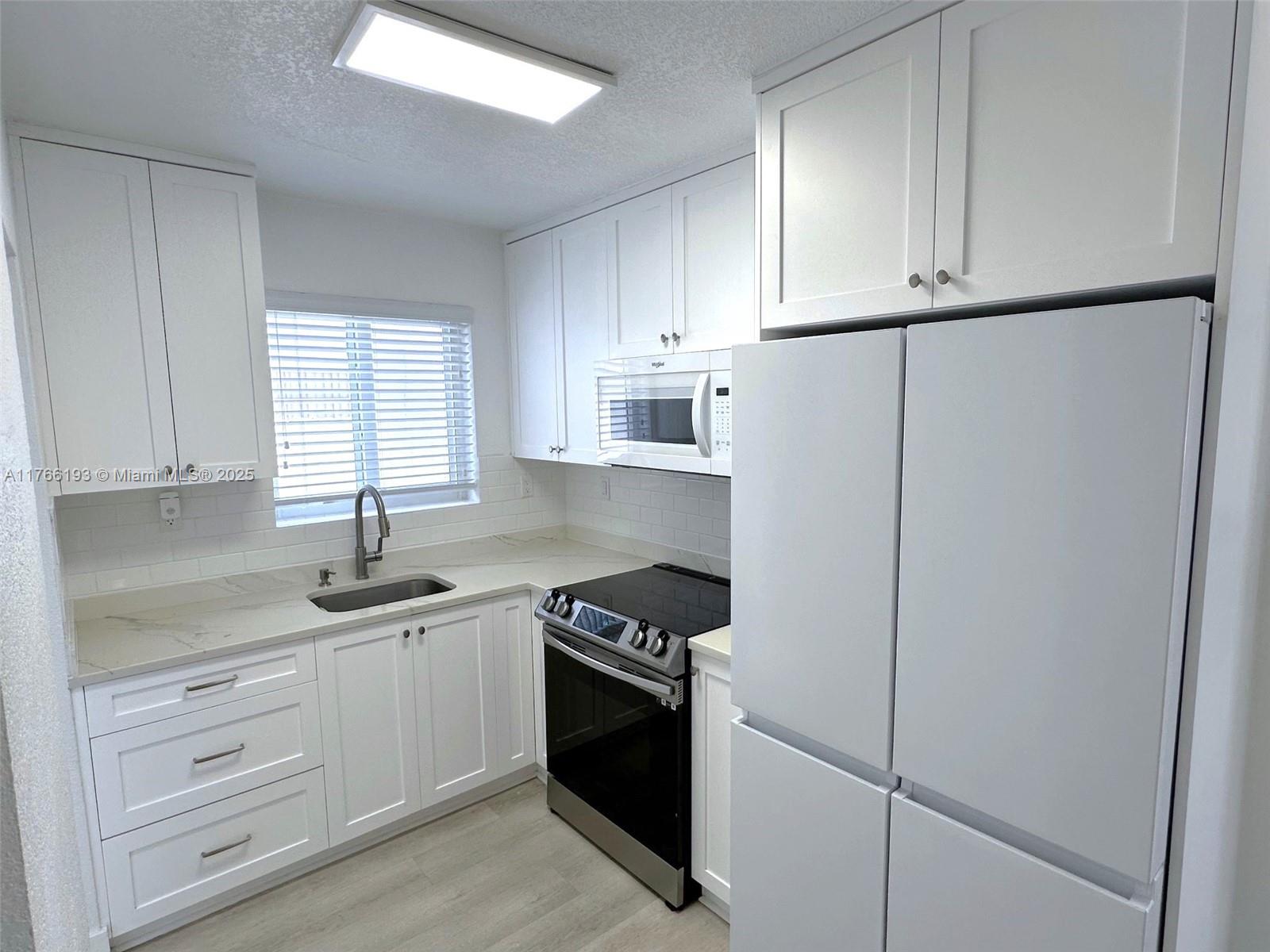 11232 Southwest 5th Street, Unit 2 Sweetwater, FL 33174 - Photo 8 of 24 a kitchen with white cabinets sink and white appliances