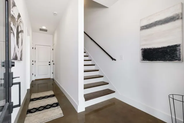 a view of a hallway with front door wooden floor and windows