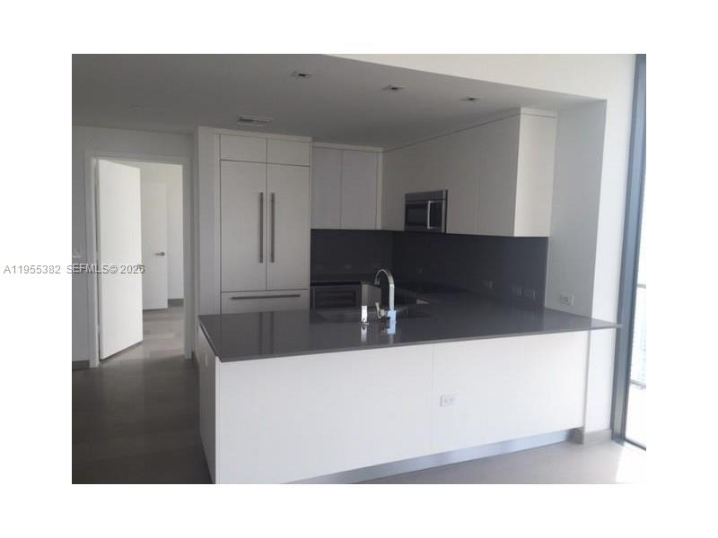 68 Southeast 6th Street, Unit 3502 Miami, FL 33131 - Photo 3 of 16 a kitchen with a sink and a refrigerator