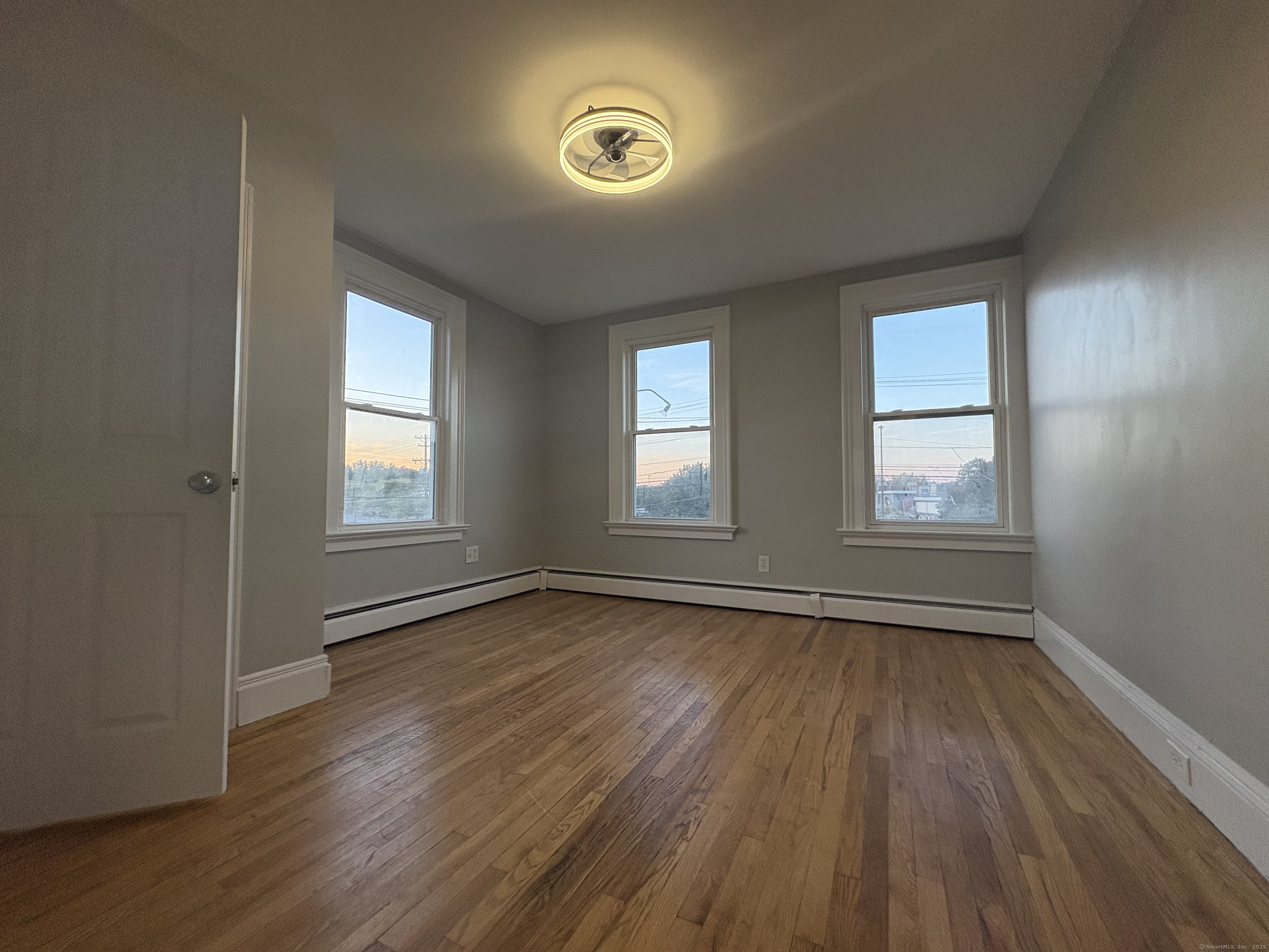 818 Pine Street, Unit 14 Bristol, CT 06010 - Photo 11 of 15 an empty room with wooden floor and windows