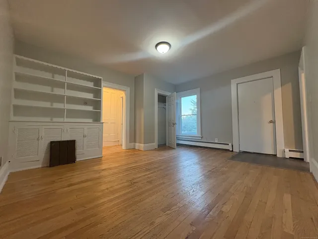 an empty room with wooden floor fireplace and windows
