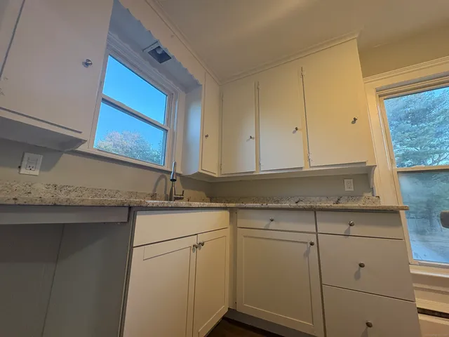 a kitchen with granite countertop white cabinets and a sink