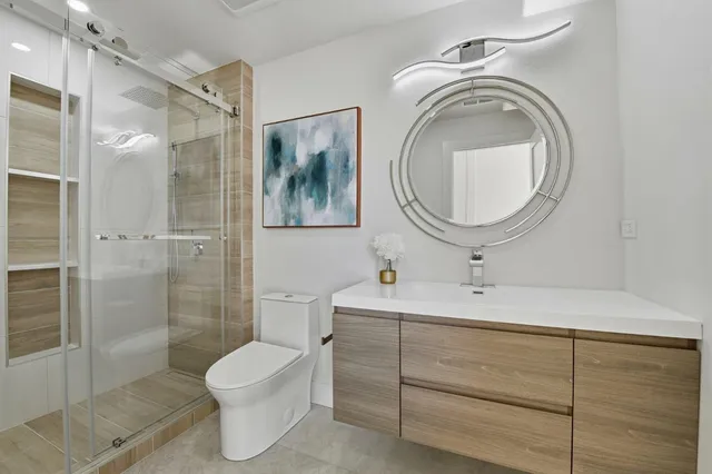 a bathroom with a toilet sink vanity granite and shower