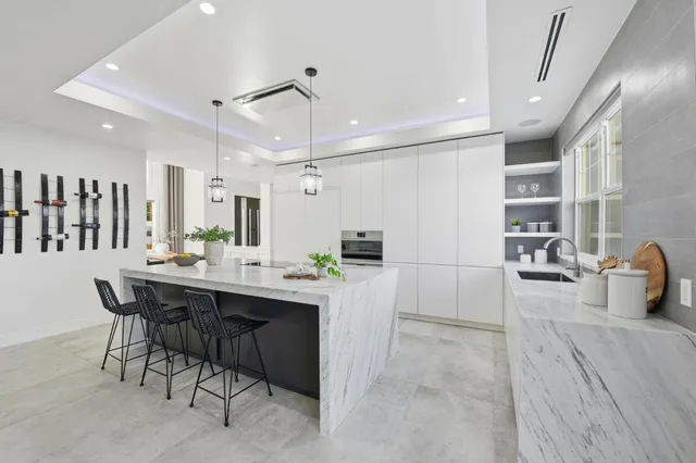 a kitchen with kitchen island a dining table chairs cabinets and sink