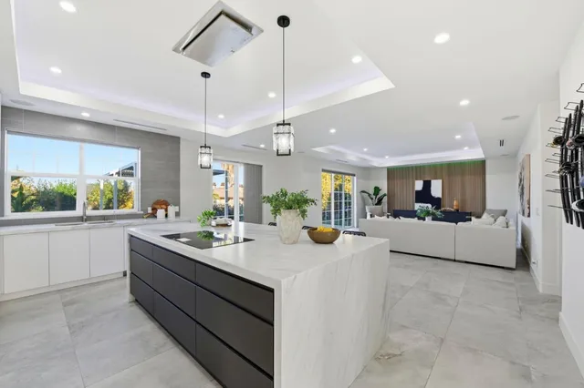 a kitchen with a sink a counter top space and living room view