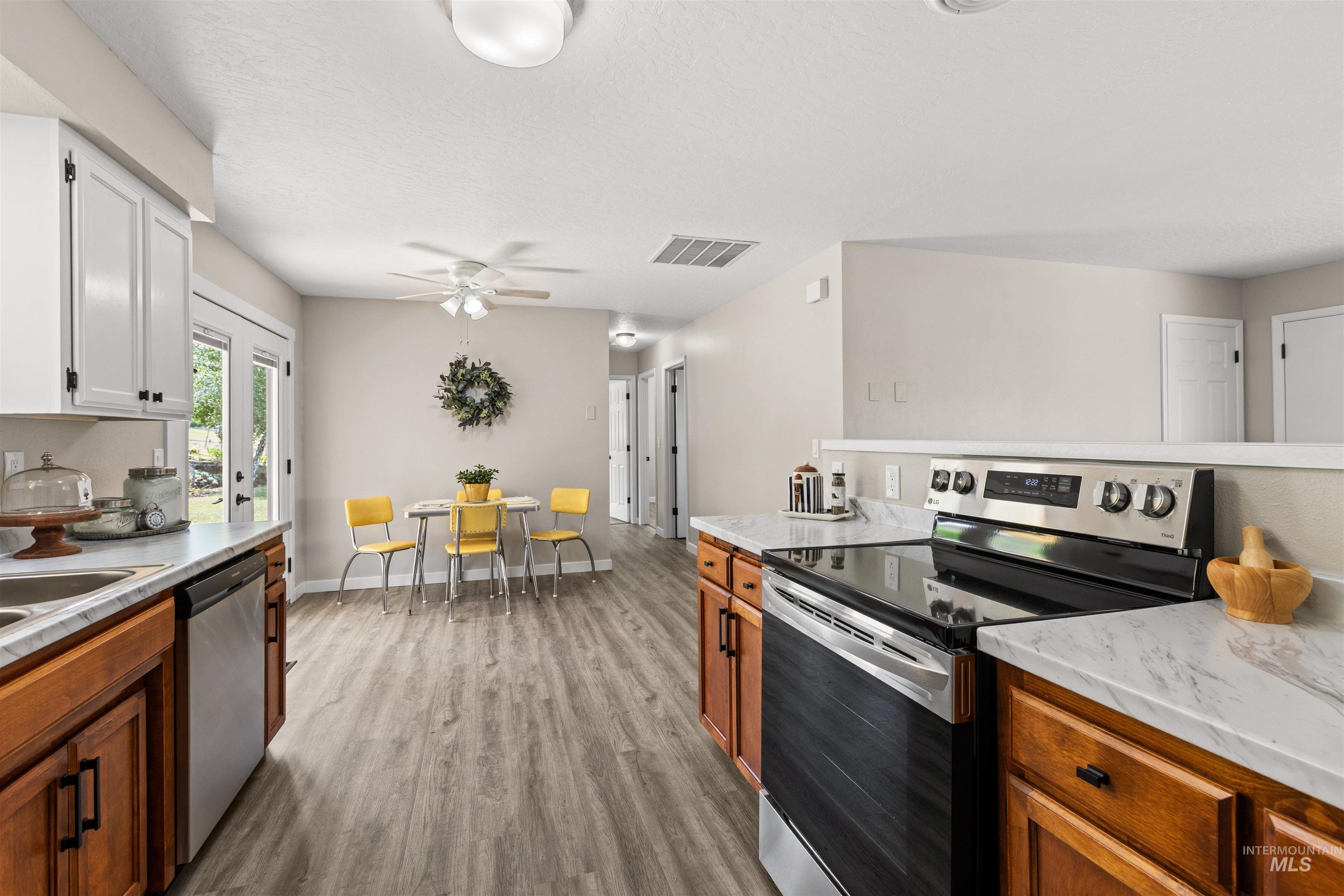 12184 Hill Road Payette, ID 83661 - Photo 16 of 35 Contemporary kitchen featuring white upper cabinetry, natural wood-finish lower cabinetry, and light-toned countertops