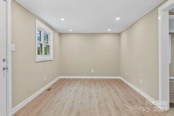 a view of an empty room with wooden floor and a window
