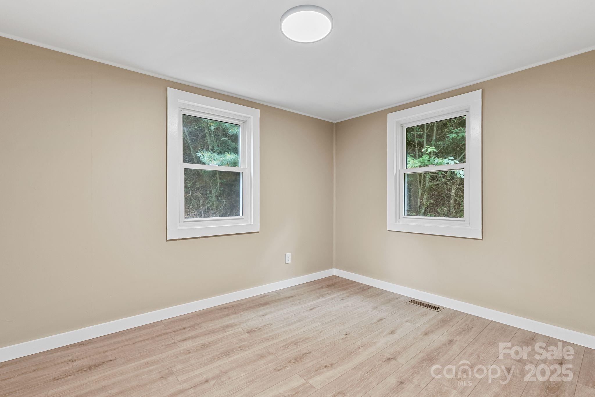 530 Rebel Ridge Road Marshall, NC 28753 - Photo 22 of 46 a view of an empty room with wooden floor and a window