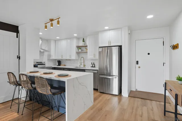 a kitchen with stainless steel appliances a dining table chairs refrigerator and sink