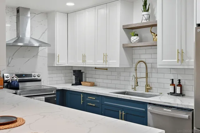 a kitchen with stainless steel appliances a stove a sink and white cabinets