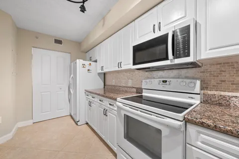 a kitchen with granite countertop stainless steel appliances white cabinets granite counter tops and a sink