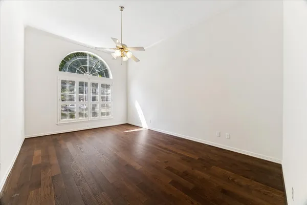 an empty room with wooden floor chandelier and windows