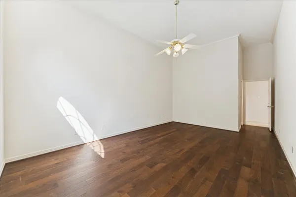 an empty room with wooden floor and ceiling fan