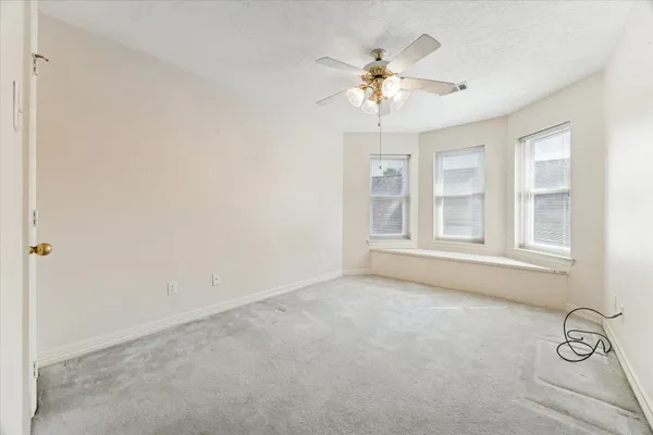 a view of an empty room with chandelier fan and wooden floor