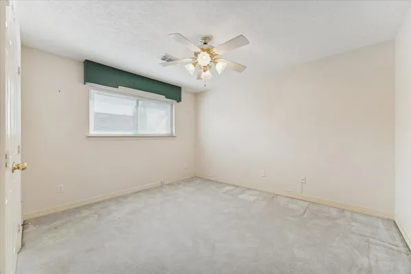 an empty room with windows and fan