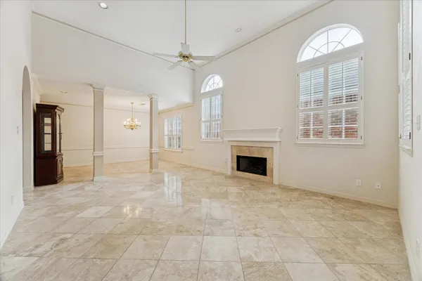 an empty room with windows chandelier and fireplace