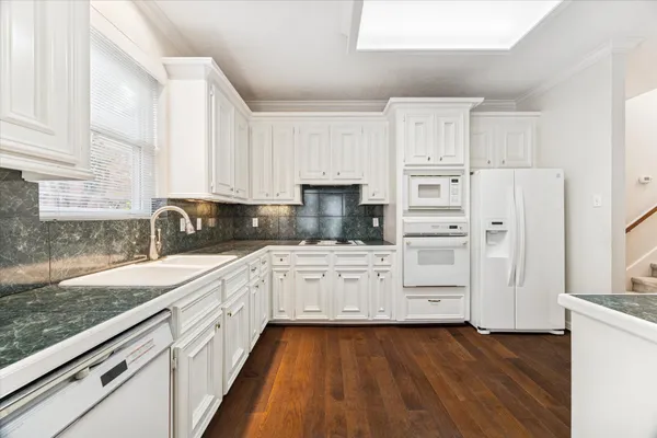a kitchen with granite countertop white cabinets and white appliances