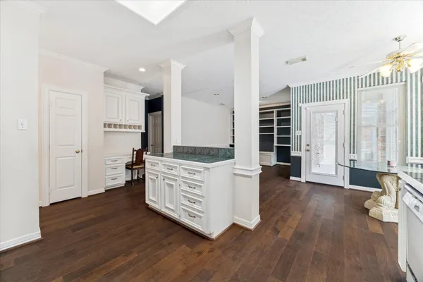 a room with kitchen island wooden floors and white walls