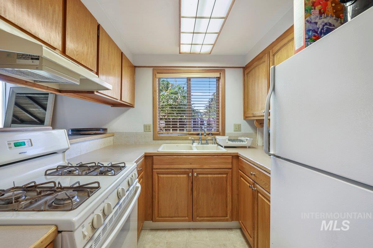1801 Y Street Heyburn, ID 83336 - Photo 28 of 42 Kitchen featuring white appliances, light countertops, brown cabinetry, and under cabinet range hood