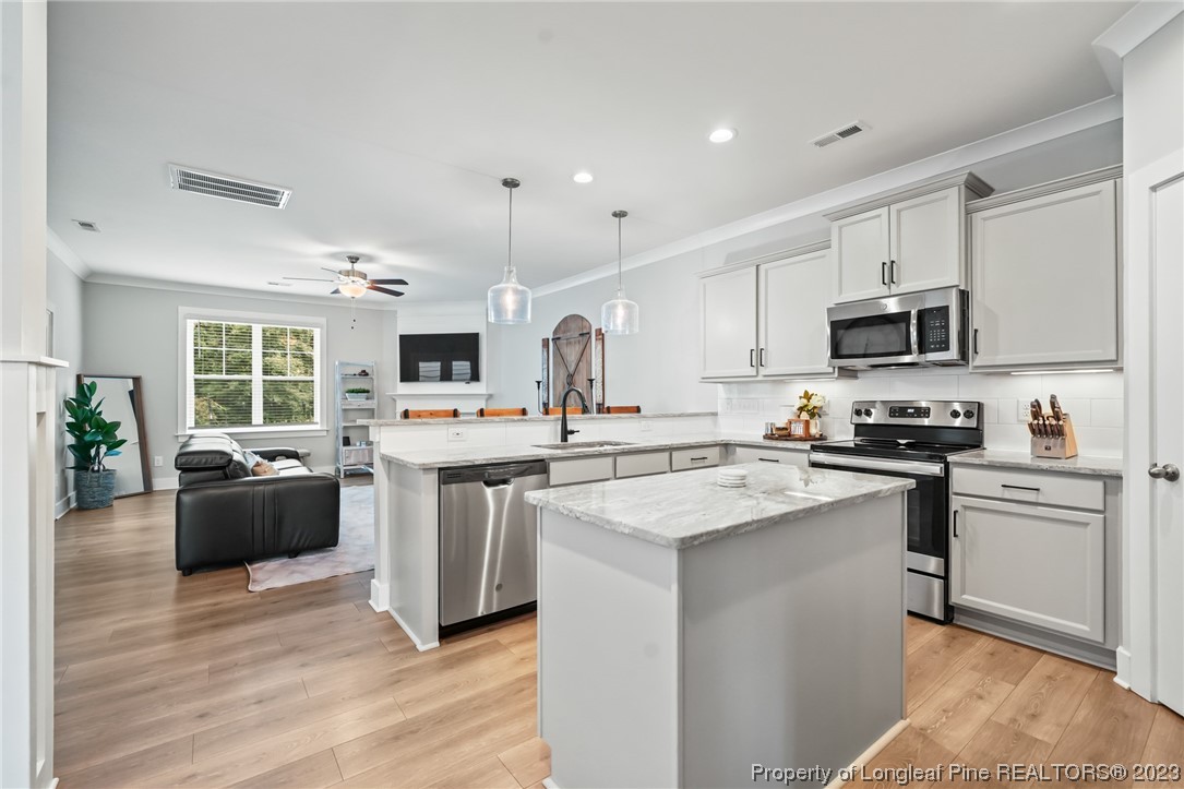 68 Spruce Hollow Circle Spring Lake, NC 28390 - Photo 8 of 48 a kitchen with stainless steel appliances granite countertop a stove top oven a sink dishwasher a refrigerator and a microwave oven with wooden floor