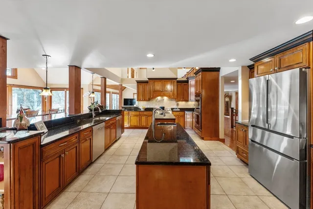a large kitchen with kitchen island a large counter top space a sink a stove and a refrigerator