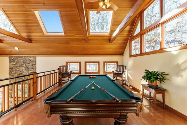 a room with wooden floor pool table and chairs