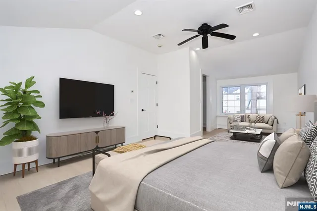 a spacious bedroom with a bed and a flat screen tv