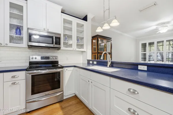 a kitchen with stainless steel appliances granite countertop a refrigerator a sink dishwasher a oven with white cabinets and wooden floor