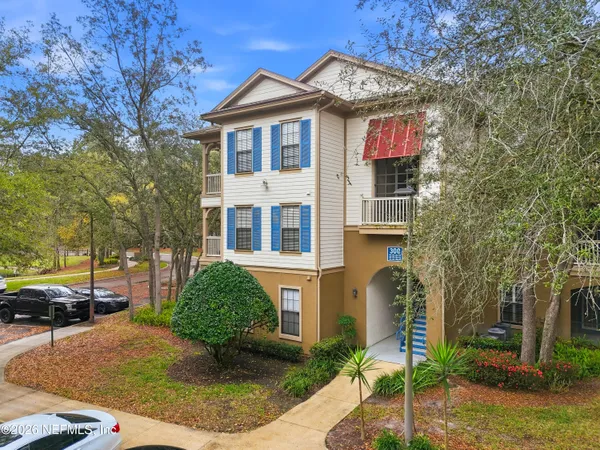 a view of a white house with a large tree