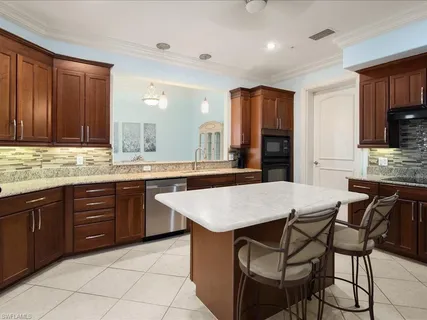 a kitchen with stainless steel appliances granite countertop a table chairs sink and cabinets