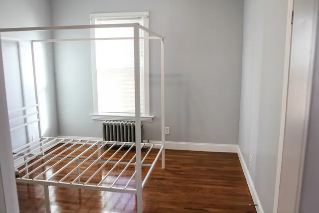 a bedroom with wooden floor and window