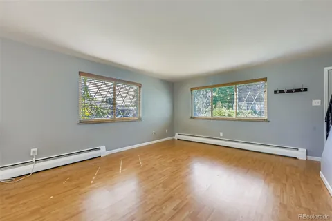 an empty room with wooden floor and windows