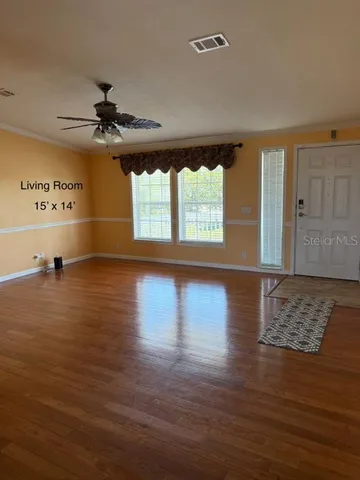 a view of an empty room with window and wooden floor
