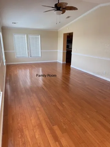 an empty room with wooden floor and a ceiling fan