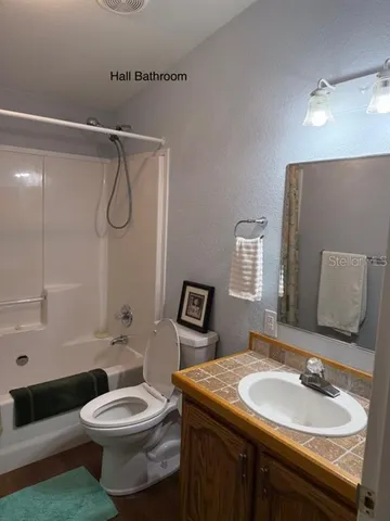 a bathroom with a granite countertop sink toilet a mirror and shower