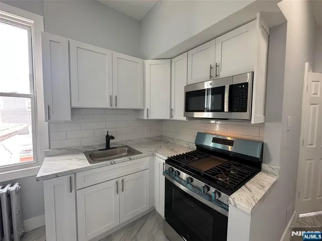 a kitchen with cabinets stainless steel appliances and a window