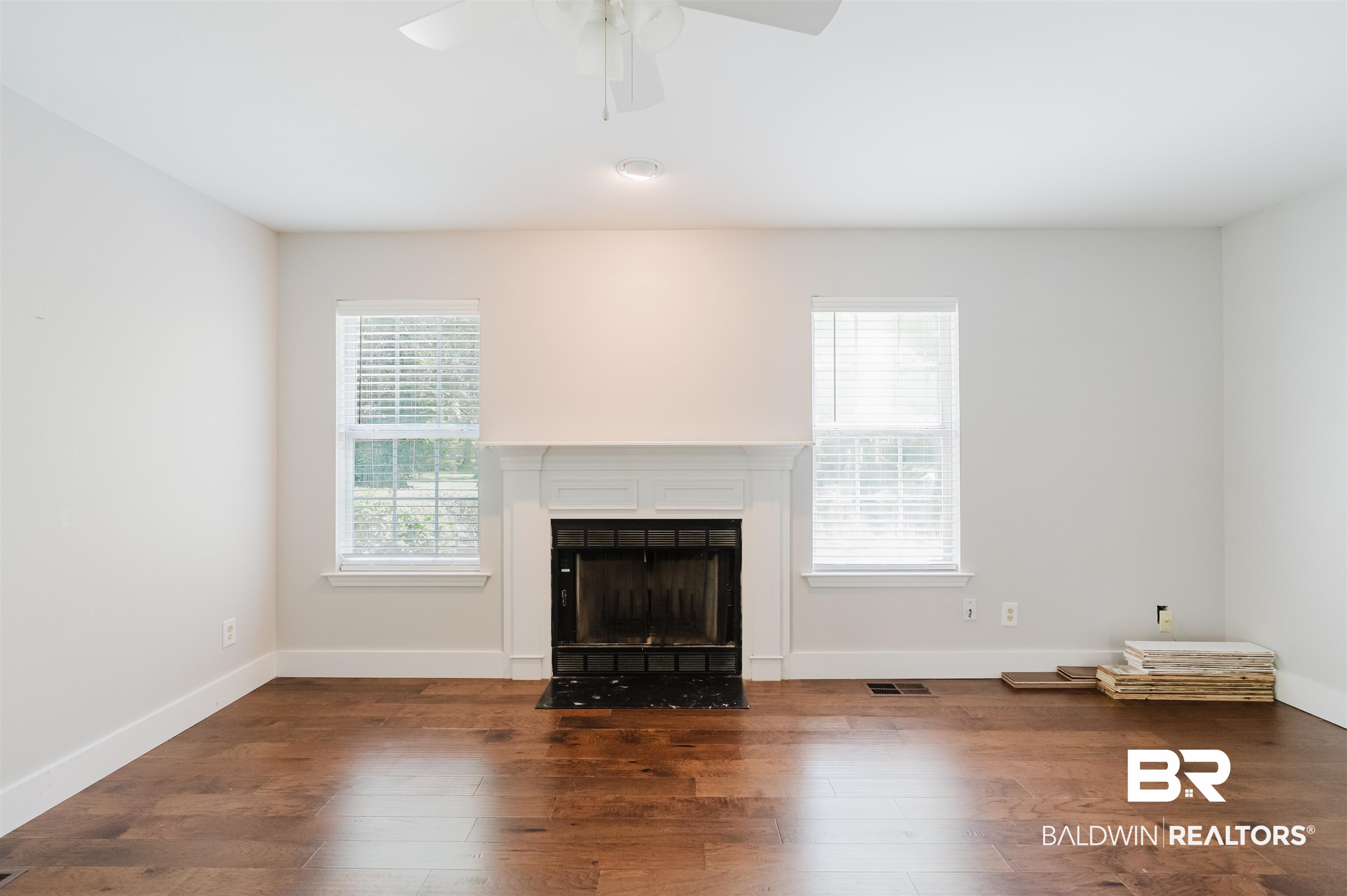 20460 Bishop Road Fairhope, AL 36532 - Photo 15 of 41 Unfurnished living room featuring a fireplace with flush hearth, a ceiling fan, wood finished floors, and baseboards