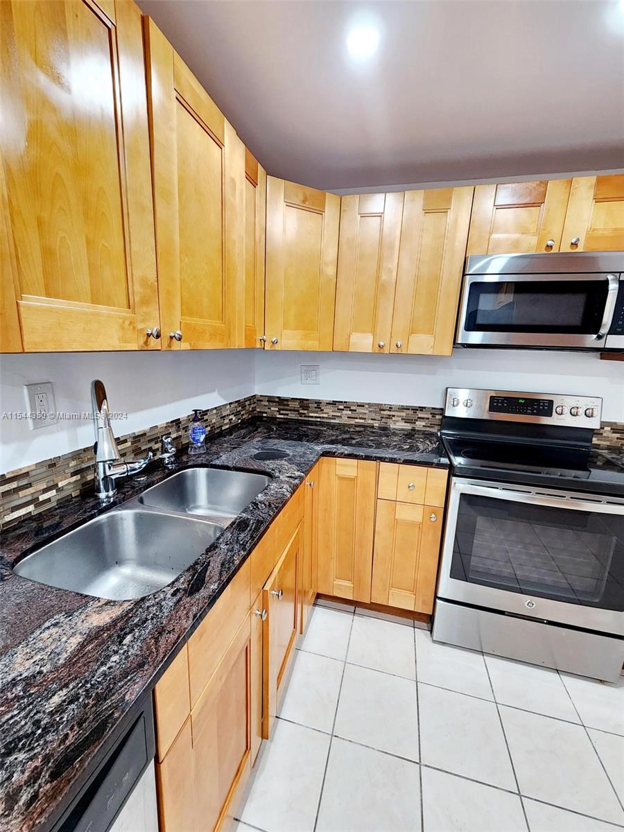 a kitchen with stainless steel appliances granite countertop a sink a stove counter space and a window