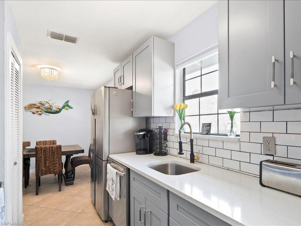 2469 Florida Avenue Naples, FL 34112 - Photo 14 of 31 Kitchen featuring gray cabinets, light tile patterned flooring, light stone countertops, backsplash, and dishwasher