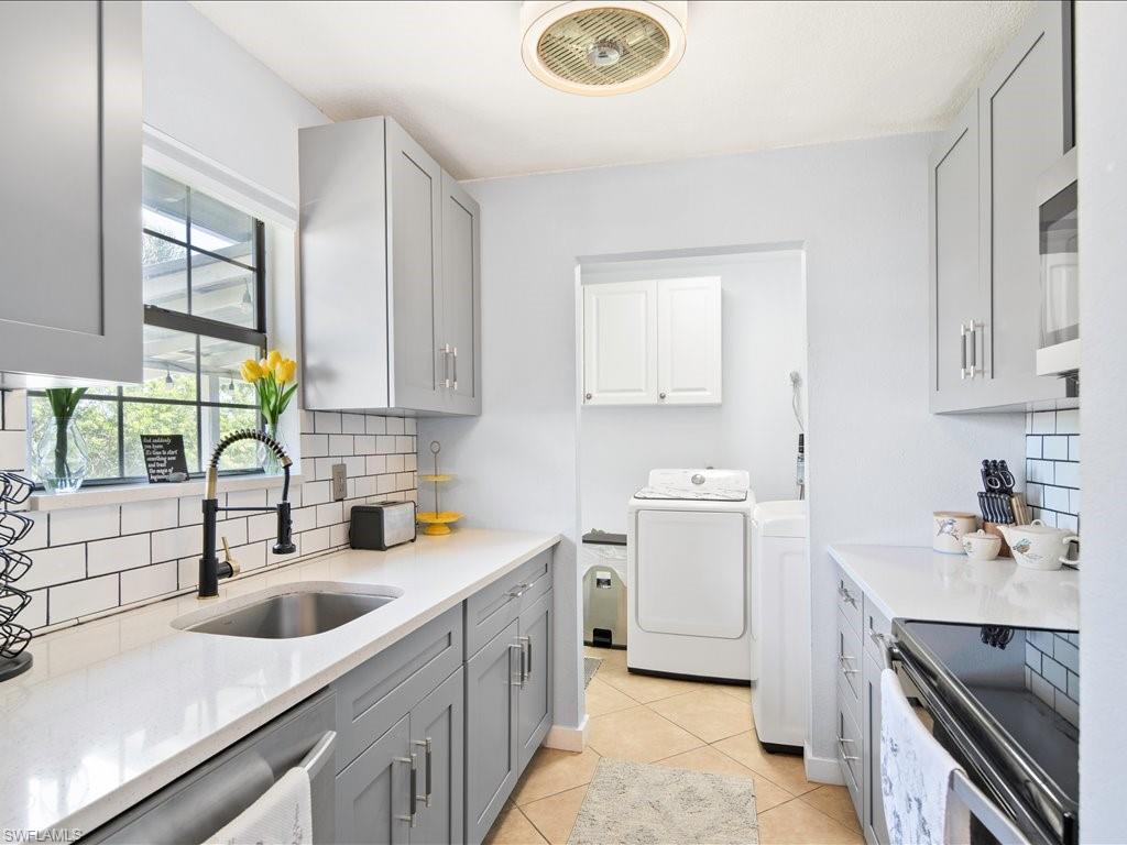 2469 Florida Avenue Naples, FL 34112 - Photo 16 of 31 Kitchen with gray cabinets, appliances with stainless steel finishes, tasteful backsplash, light stone countertops, and washer and dryer